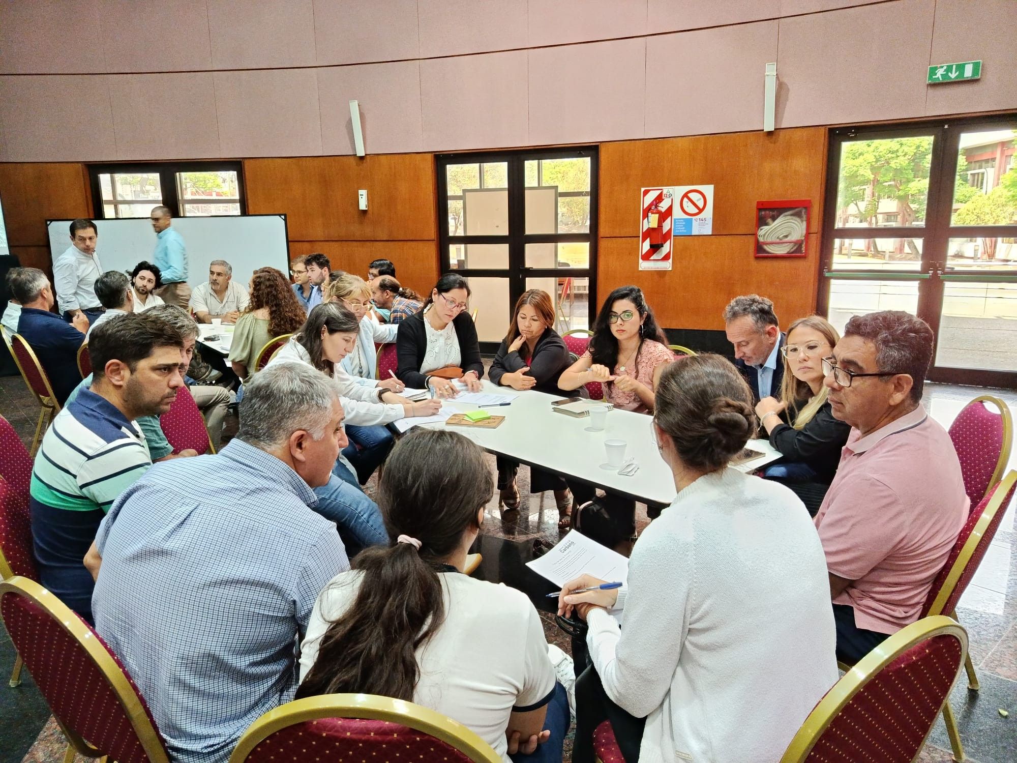 Equipos técnicos trabajan en mesas con mapas durante una jornada de planificación.